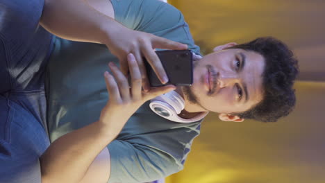Vertical-video-of-Man-using-social-media-on-phone-laughing-at-night-at-home.